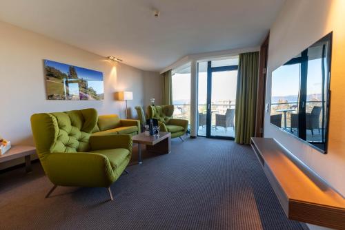 ユーバーリンゲンにあるパークホテル ザンクト レオンハルトのリビングルーム(緑の椅子、大きな窓付)