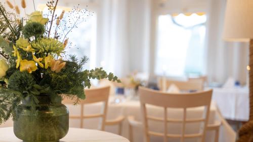 a vase of flowers on a table with chairs at Parkhotel St.Leonhard in Überlingen
