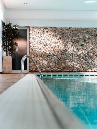a swimming pool in a house with a stone wall at Parkhotel St.Leonhard in Überlingen