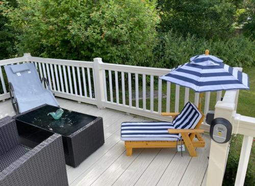 a patio with a chair and an umbrella and a table at Poppy at Oakdene Forest Park in Ringwood