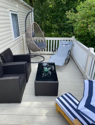 a deck with chairs and a table and a fish tank at Poppy at Oakdene Forest Park in Ringwood