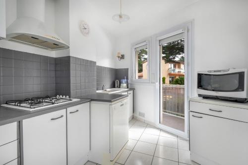 une cuisine blanche avec un évier et un micro-ondes dans l'établissement Emplacement idéal en front de mer, à La Baule