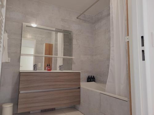 ein Badezimmer mit Badewanne, Waschbecken und Spiegel in der Unterkunft Chez Patron T3 2BR with 2 parking near Disneyland Paris & train station-Chessy in Chessy