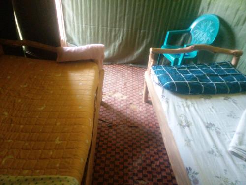 a room with two chairs and a bed with a mattress at Mbunga Community Tourism Campsite in Kasese