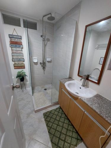 a bathroom with a sink and a shower with a mirror at 1 bedroom with balcony near airport in Mactan