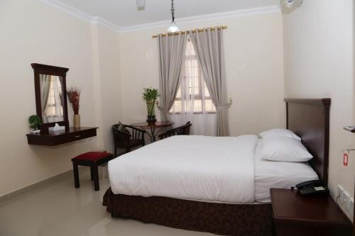 a bedroom with a white bed and two windows at Jarzez Hotel Apartments Al Hail in Seeb