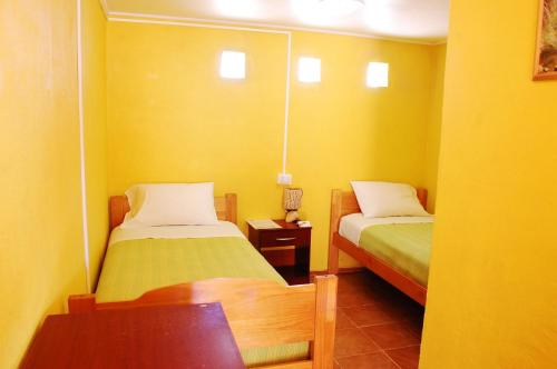 a small room with two beds and a table at Hostal Miskanty in San Pedro de Atacama