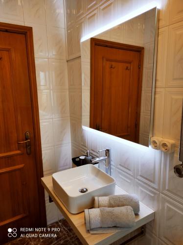 y baño con lavabo y espejo. en Casa Além Rio - quartos para 6 hóspedes em Santo Tirso en Santo Tirso