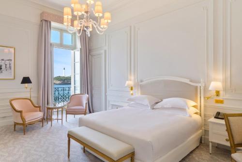 a bedroom with a large white bed and a chandelier at Hôtel du Palais Biarritz, in The Unbound Collection by Hyatt in Biarritz