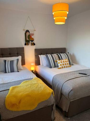 sypialnia z 2 łóżkami i żółtym kocem w obiekcie Stay at The Penn! 5 Bedroomed home in Treharris w mieście Treharris