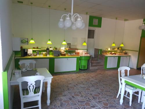 a large kitchen with green cabinets and white tables and chairs at Hotel/Pension Rast& Ruh in Zodel