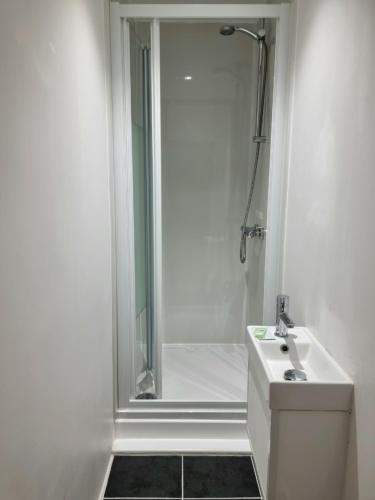 a white bathroom with a shower and a sink at Park View House in Edinburgh