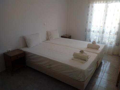 een slaapkamer met een wit bed en 2 handdoeken bij La Cite Family Hotel & Apartments in Moraitika