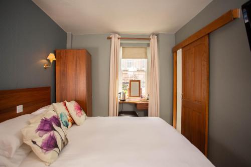 een slaapkamer met een wit bed en een raam bij Queens Head Hotel in Berwick-Upon-Tweed