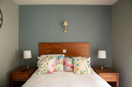 a bedroom with a bed with pillows and two lamps at Queens Head Hotel in Berwick-Upon-Tweed