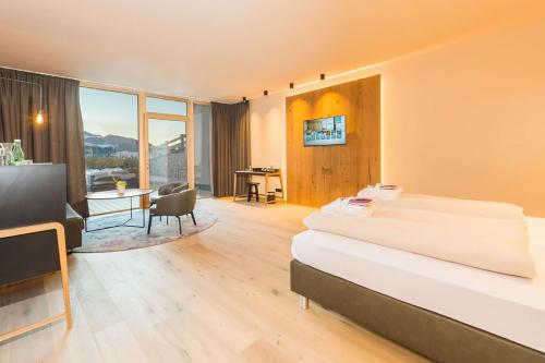 a hotel room with a bed and a desk and a television at Hotel Penzinghof in Oberndorf in Tirol