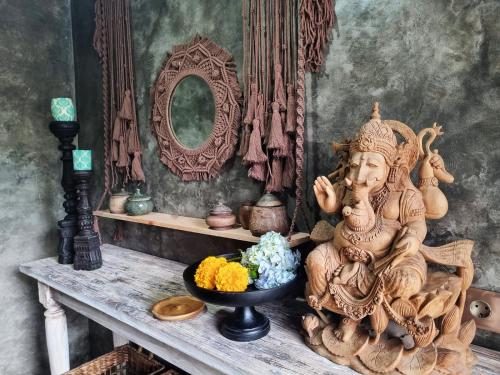 坎古的住宿－Stay at My Place Bali，坐在桌子上的雕像,放着一碗鲜花