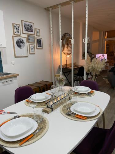 a white table with plates and wine glasses on it at Les Apparts de la Bastide 35A in Villeneuve-sur-Lot
