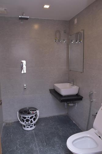 a bathroom with a sink and a toilet and a mirror at Hotel Bluestone in Srikalahasti