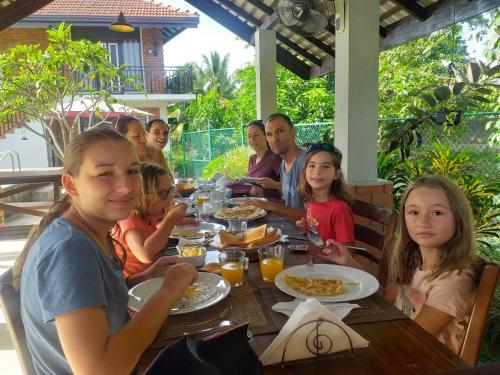 a group of people sitting at a table eating food at Green Wood Villa Negombo in Negombo
