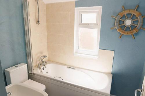 a bathroom with a tub and a toilet and a window at Lovely, Cosy Beachside Cottage 1 - Perfect Location in Llandudno