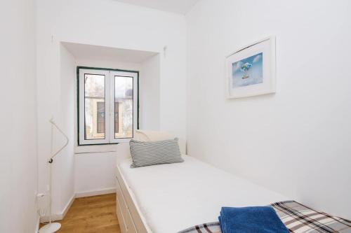 een witte kamer met een bed en een raam bij Ola Lisbon - Alfama III in Lissabon