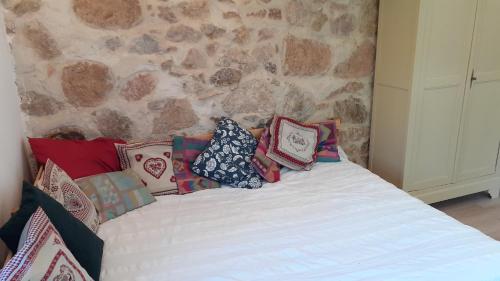 a bed with pillows on it with a stone wall at Le Studio du Crot Noir in Cussy-en-Morvan