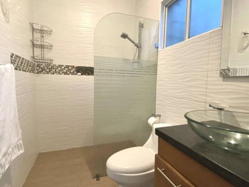 a bathroom with a toilet and a glass sink at Casa con Parqueo Privado, Patio y Jacuzzi. in Santo Domingo