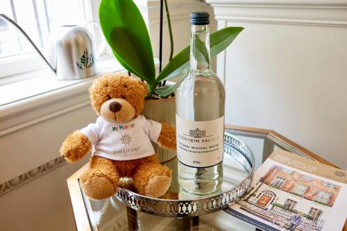 a teddy bear sitting on a glass table next to a bottle of wine at 9 Hertford Street - 4 Stars VisitEngland in London