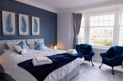 a bedroom with a large bed and two blue chairs at Lovely, Cosy Beachside Cottage 1 - Perfect Location in Llandudno