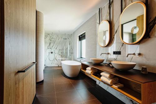 a bathroom with two sinks and two mirrors at Van der Valk Hotel Schiedam in Schiedam