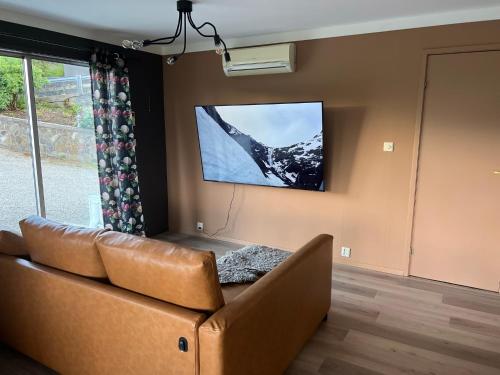 Feriehus i Flekkefjord med panoramautsikt في فليكهافيود: غرفة معيشة مع أريكة وتلفزيون بشاشة مسطحة