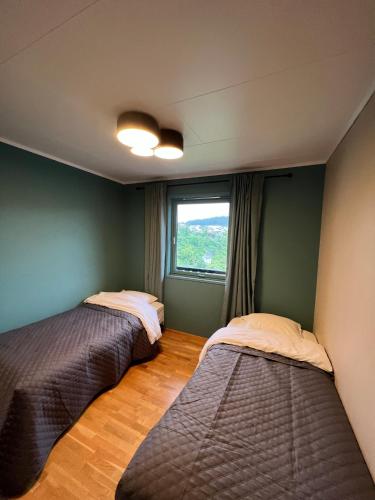 two beds in a room with a window at Feriehus i Flekkefjord med panoramautsikt in Flekkefjord