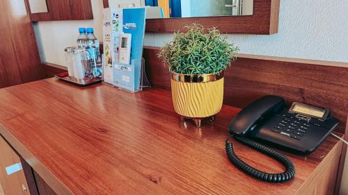 a desk with a phone and a potted plant on it at Aqua Hotel in Polkowice