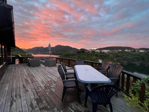 a table and chairs on a deck with a sunset at Feriehus i Flekkefjord med panoramautsikt in Flekkefjord