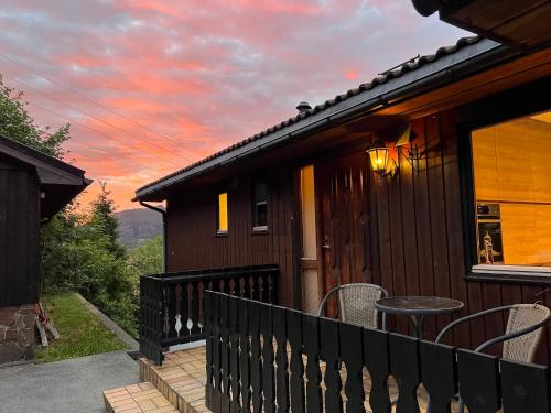 Feriehus i Flekkefjord med panoramautsikt في فليكهافيود: منزل مع شرفة مع طاولة وغروب الشمس
