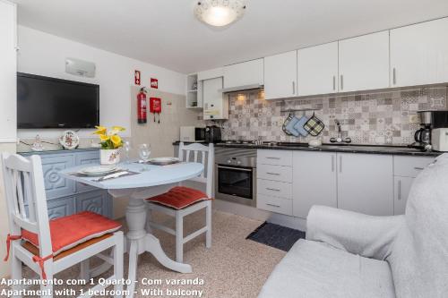 a kitchen with white cabinets and a white table and chairs at Akisol Lagos Beach in Burgau