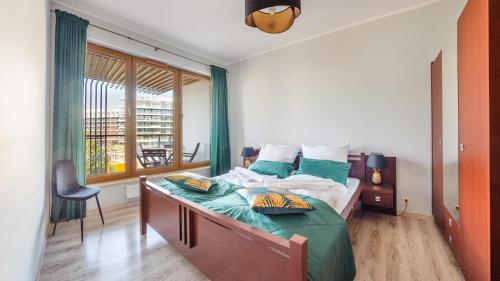 a bedroom with a bed with green sheets and a window at Olympic Park I, Sun & Snow in Kołobrzeg