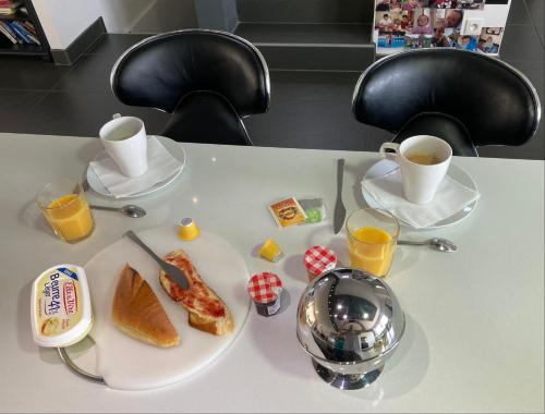una mesa con un plato de comida y dos tazas de café en B&B Chez l'habitant Chambre Privative Sur La Route Des Vins Tv Parking box vélo bike, en Issenheim