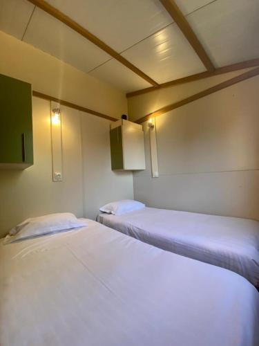 two beds in a room with white sheets at Coimbra Camping & Bungalows in Coimbra
