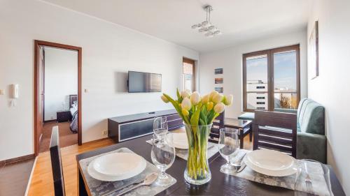 a dining room with a table with a vase of flowers at Olympic Park I, Sun & Snow in Kołobrzeg