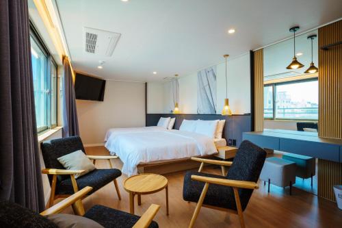 a bedroom with a bed and chairs and a desk at Hotel Pico in Tongyeong