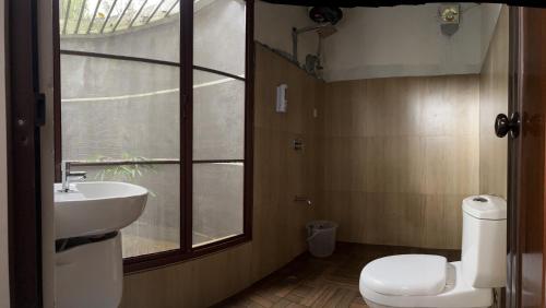 Un baño con inodoro, lavabo y ventana. en LAZY RETREAT, en Vagamon