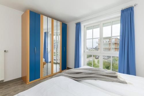 シャルボイツにあるHanseaten Residenz App 19のベッドルーム1室(青いカーテン、ベッド1台、窓付)