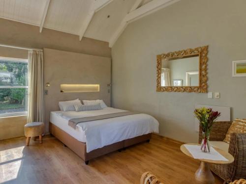 a bedroom with a bed and a mirror and a couch at Explorer Guesthouse in Somerset West
