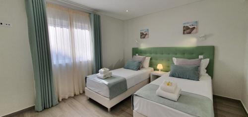1 dormitorio con 2 camas y ventana en Beach View Vela House, en Albufeira