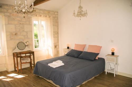 a bedroom with a bed and a table and a chandelier at ENTRE PIERRE ET BOIS in Saint-Savinien