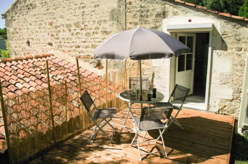 a table and chairs under an umbrella on a patio at ENTRE PIERRE ET BOIS in Saint-Savinien