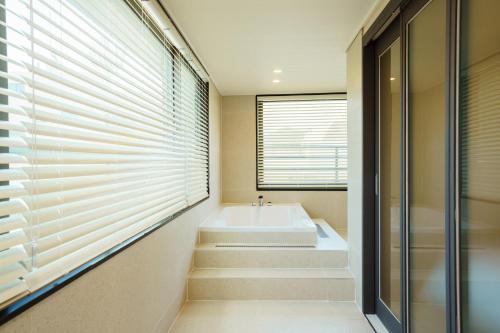 a bathroom with a bath tub and a window at Hotel Pico in Tongyeong