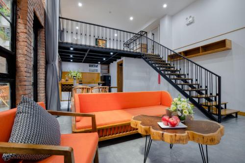 a living room with orange furniture and a staircase at Flexi Hotel & Apartment Han Market in Da Nang